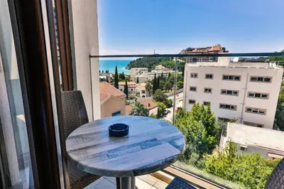 a table on a balcony with a view of a city at Hotel Lusso Mare by Aycon in Budva