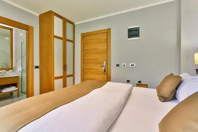 a bedroom with a large white bed and a bathroom at Hotel Lusso Mare by Aycon in Budva