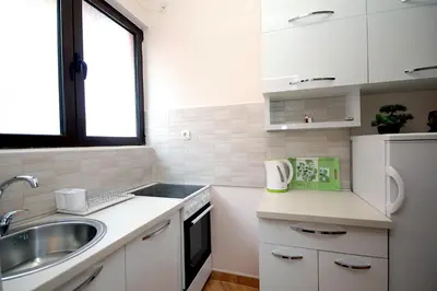 a small kitchen with white cabinets and a sink at Apartments Radosavovic in Bar