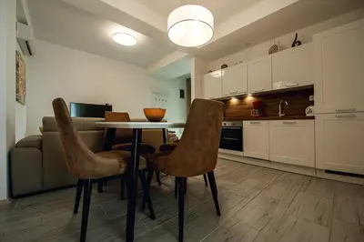 a kitchen with a table and chairs in a room at Adria Lux Apartments Sveti Stefan in Budva