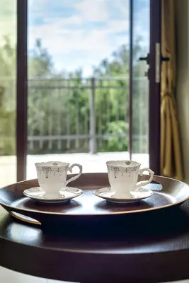 two coffee cups sitting on a table with a window at Adria Lux Apartments Sveti Stefan in Budva