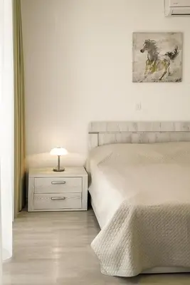 a white bedroom with a bed and a lamp on a night stand at Adria Lux Apartments Sveti Stefan in Budva
