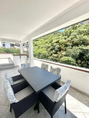 a dining room with a table and chairs and a large window at Apartments Harmonija in Budva