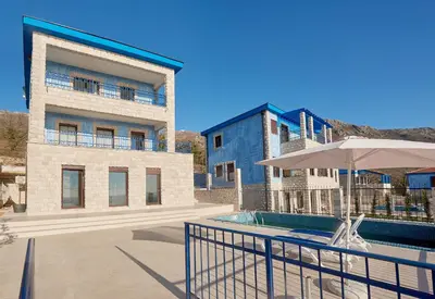 a building with a swimming pool and an umbrella at Sunbreeze Delux Vilas in Budva