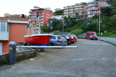 a red boat is parked in a parking lot at Vanessa Apartment in Budva