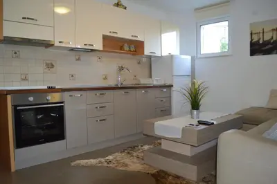 a kitchen with white cabinets and a living room at Vanessa Apartment in Budva
