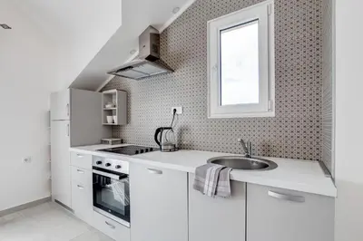 a white kitchen with a sink and a window at Sunny Nest Apartments in Kotor