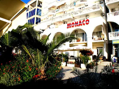 a large white building with plants in front of it at Apartments Stević - Monaco in Budva