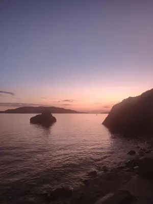 a sunset over a body of water with a rock in it at Apartments Stević - Monaco in Budva