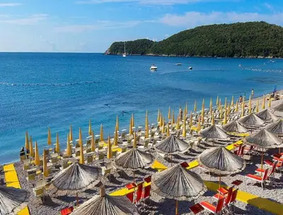 a beach with many umbrellas and the ocean at Villa Merci Budva in Budva
