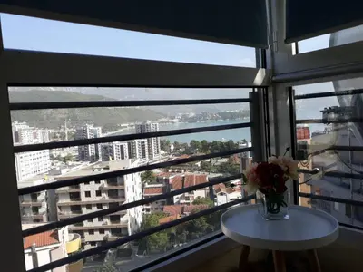 a vase of flowers on a table in front of a window at Seaview Paradise Apartment in Budva