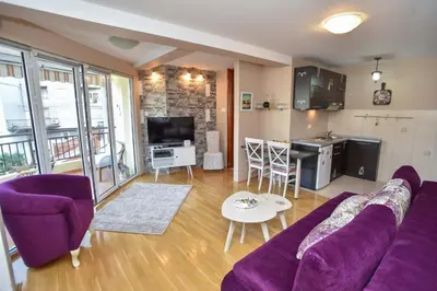 a living room with a purple couch and a kitchen at Seaview Paradise Apartment in Budva