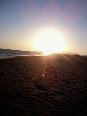 a sunset on a beach with the sun setting at Apartments EMERALD in Ulcinj