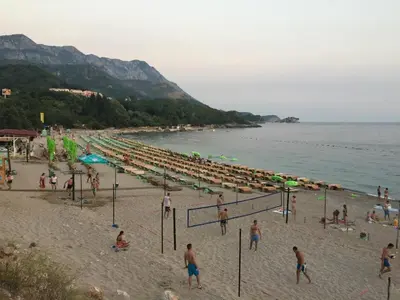 a group of people on a beach near the water at Apartmani Dragović in Sveti Stefan