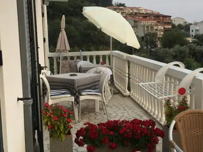 a table and chairs on a balcony with an umbrella at Apartmani Dragović in Sveti Stefan