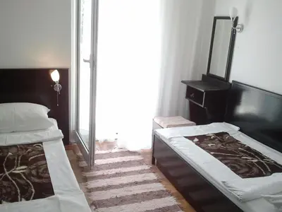 a bedroom with two beds and a mirror at Apartmani Dragović in Sveti Stefan
