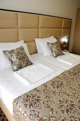a large bed with white sheets and pillows at Hotel Lion in Ulcinj