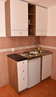 a kitchen with white cabinets and a sink at Apartments Simun in Kotor