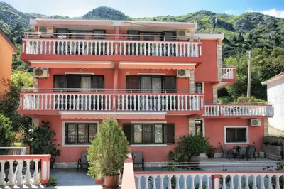 a red house with a balcony on top of it at Apartments Simun in Kotor