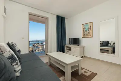 a living room with a couch and a table and a window at Apartments Jovan in Sveti Stefan