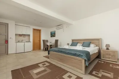 a bedroom with a large bed and a kitchen at Apartments Jovan in Sveti Stefan