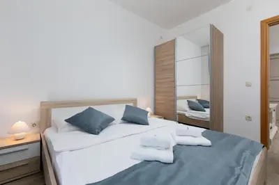 a bedroom with a large white bed with blue pillows at Apartments Jovan in Sveti Stefan
