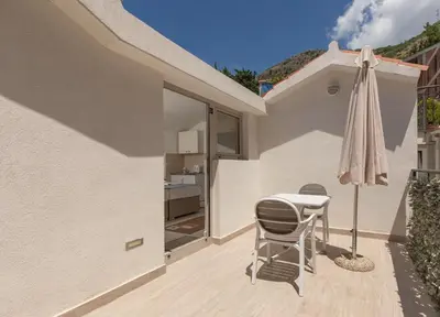 a patio with a table and chairs and an umbrella at Apartments Jovan in Sveti Stefan