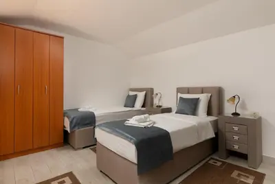 a bedroom with two beds and a wooden cabinet at Apartments Jovan in Sveti Stefan
