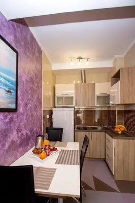 a kitchen with a white table and a purple wall at SunSea Apartments in Budva