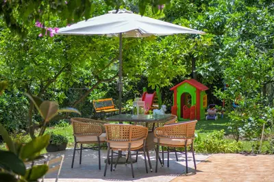 a table and chairs under an umbrella in a garden at Apartments Elena in Budva