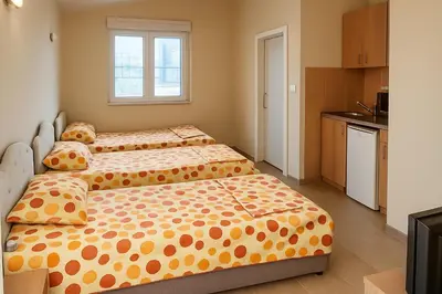 two beds in a small room with a kitchen at Apartments Lejla in Dobra Voda