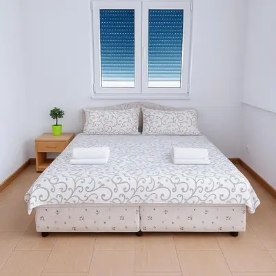 a bed in a white room with a window at Apartments Lejla in Dobra Voda