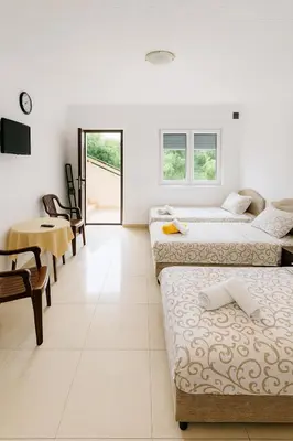 a room with three beds and a table and a desk at Apartments Lejla in Dobra Voda