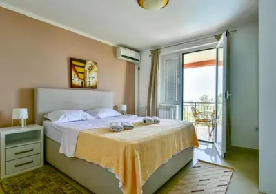 a bedroom with a large bed and a balcony at Apartments Kentera LUX in Sveti Stefan