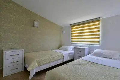 a bedroom with two beds and a window with a shutter at Apartments Kentera LUX in Sveti Stefan