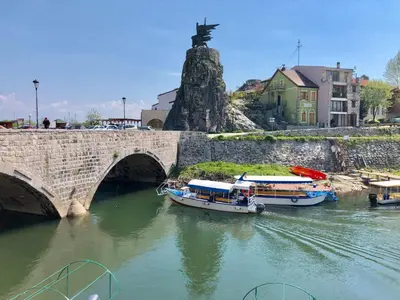 two boats in the water under a bridge at Apartments FLORA and boat cruising in Virpazar