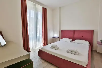 a bedroom with a red bed with two towels on it at Royal Gardens Paradise in Budva