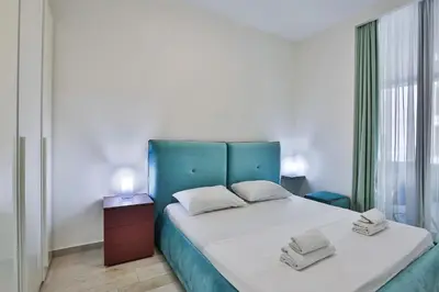 a bedroom with a large bed with a blue headboard at Royal Gardens Paradise in Budva