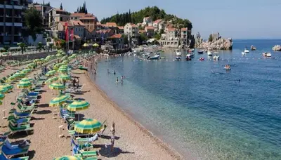 a beach with a bunch of umbrellas and people in the water at Luxury Pool Apartments near the sea in Sveti Stefan