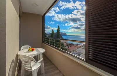 a balcony with a table and chairs and a large window at Apartment Sidro in Petrovac na Moru