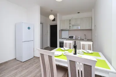 a kitchen with a table and chairs and a white refrigerator at Apartment Sidro in Petrovac na Moru