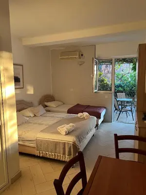 a bedroom with two beds and a table and chairs at Apartments Aleksandar in Sveti Stefan
