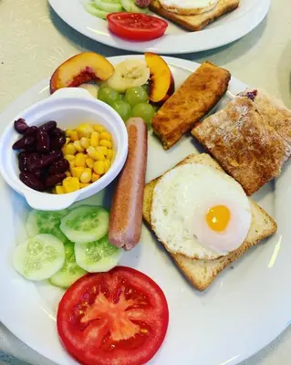 a plate of breakfast food with an egg and vegetables at Apartments Tati in Ulcinj