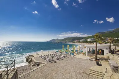 a beach with a group of chairs and the ocean at Apartments Palma in Dobra Voda