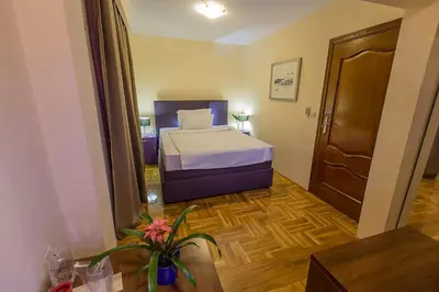 a small bedroom with a bed and a wooden floor at Hotel M in Podgorica