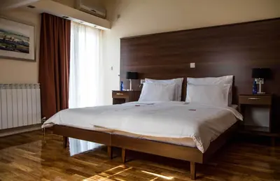 a bedroom with a large bed with a wooden headboard at Hotel M in Podgorica