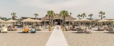 a beach with umbrellas and people on the beach at Lanika Apartments in Ulcinj