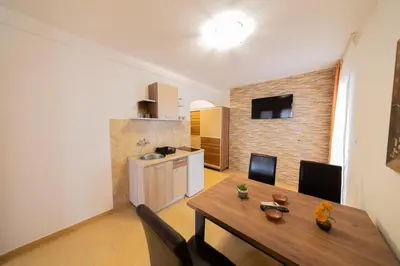a kitchen with a wooden table and chairs in a room at Azzuro apartments Budva in Budva