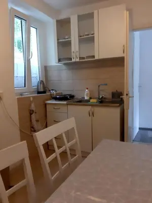a kitchen with white cabinets and a table and chairs at vicky 1 in Kotor