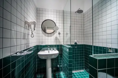 a green and white bathroom with a sink and a mirror at Hotel Marienplatz Podgorica in Podgorica